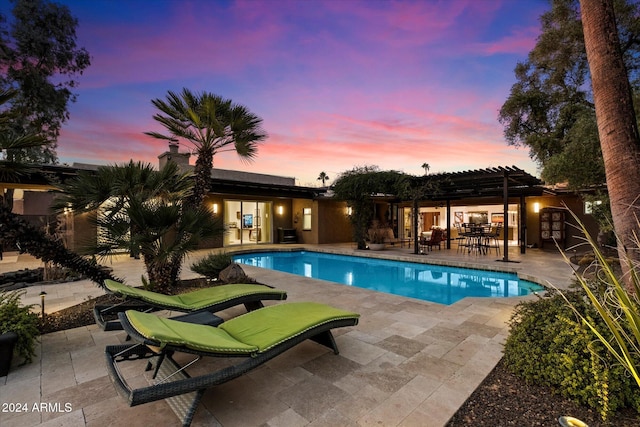 pool at dusk featuring a pergola and a patio area