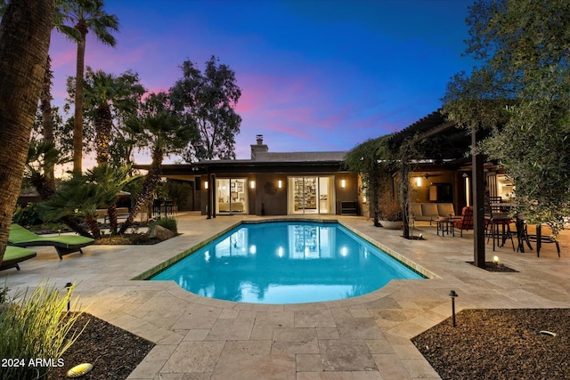 pool at dusk featuring a patio area