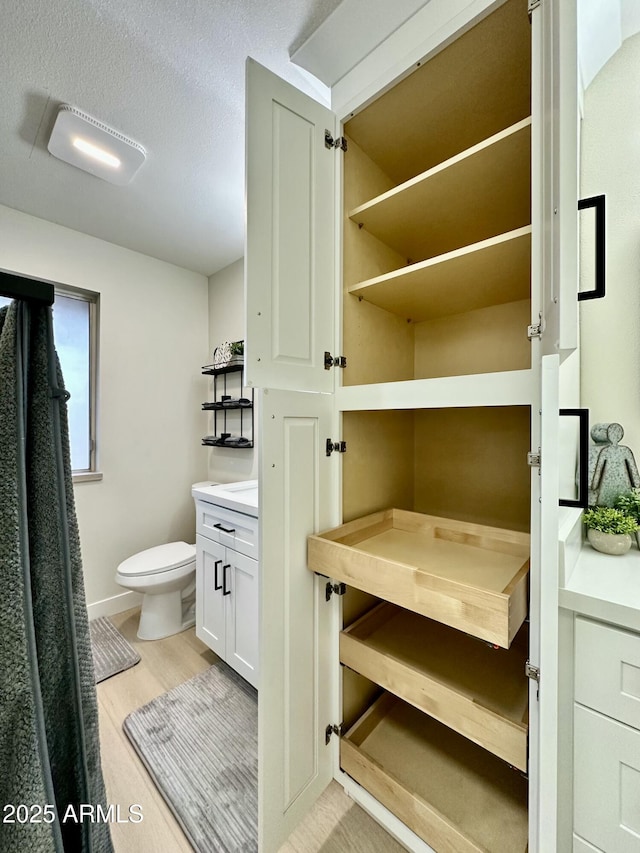 bathroom with vanity, toilet, hardwood / wood-style floors, and a textured ceiling