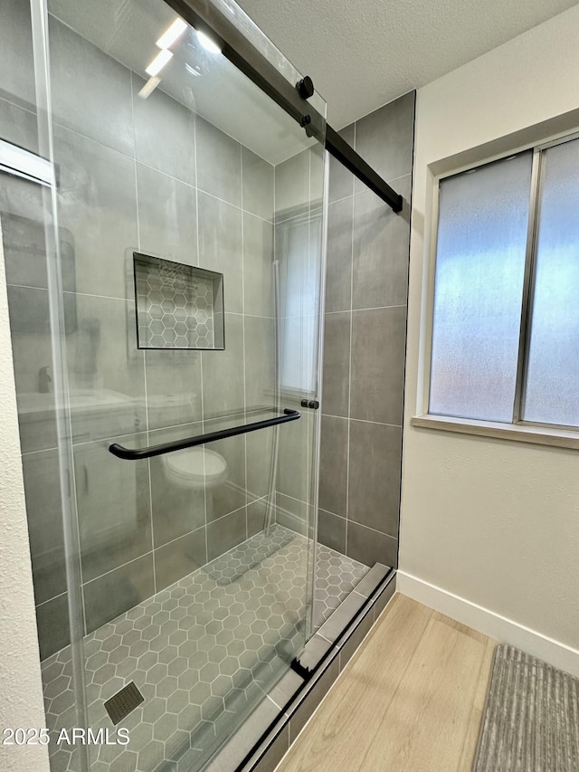 bathroom featuring a shower with shower door, a textured ceiling, and hardwood / wood-style flooring