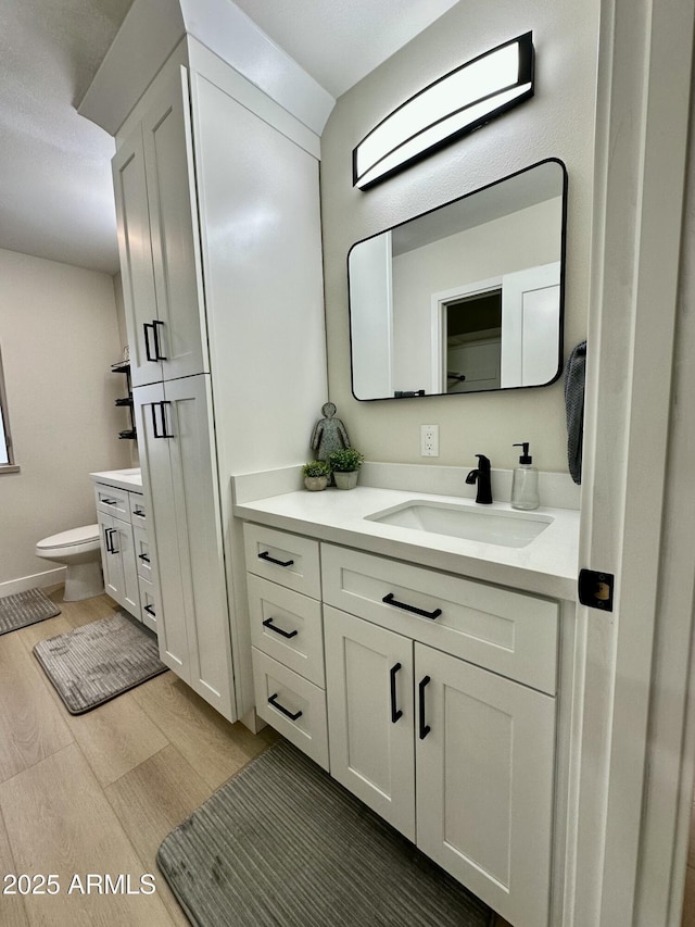 bathroom with hardwood / wood-style flooring, toilet, and vanity