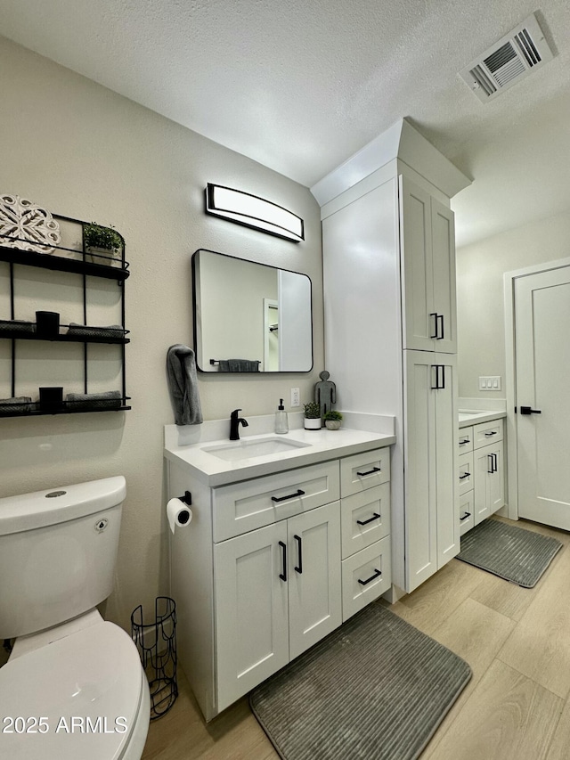 bathroom with vanity, toilet, and a textured ceiling