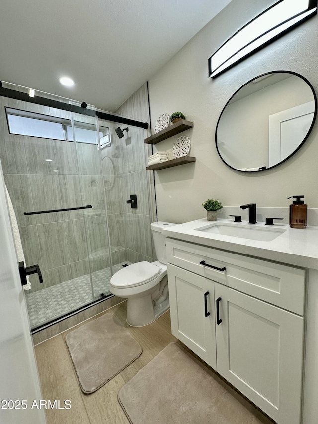 bathroom with toilet, a shower with shower door, and vanity