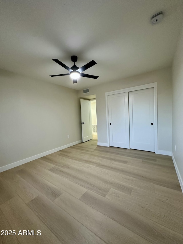 unfurnished bedroom with ceiling fan, a closet, and light hardwood / wood-style flooring