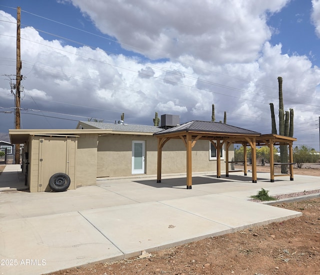144 N Cactus Rd, Apache Junction, AZ 85119 - rear view of house featuring a gazebo, stucco siding, cooling unit, a patio area, and a standing seam roof