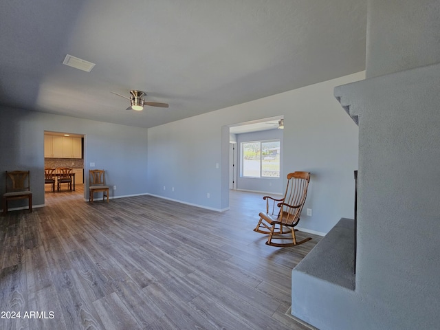 living area featuring visible vents, wood finished floors, a ceiling fan, and baseboards