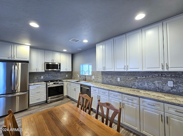 kitchen with stainless steel appliances, white cabinets, a sink, and visible vents