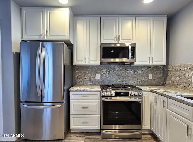 kitchen with stainless steel appliances, light stone counters, decorative backsplash, and white cabinets