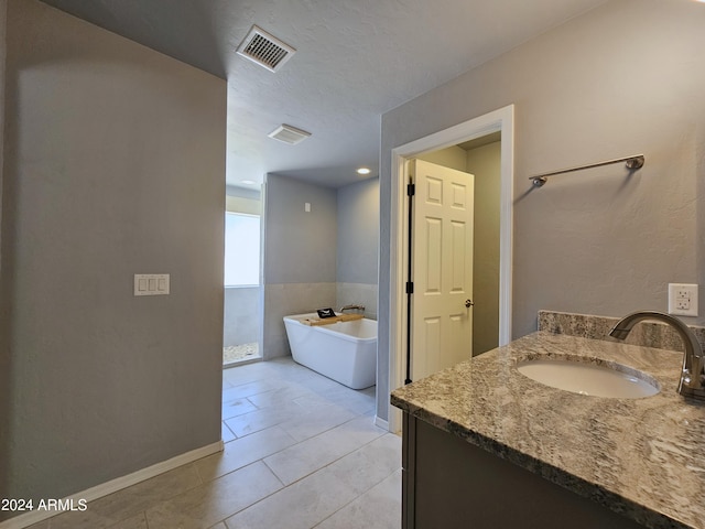 full bath with a freestanding tub, vanity, visible vents, and tile patterned floors