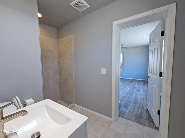 full bath with tile patterned flooring, a sink, visible vents, baseboards, and tiled shower