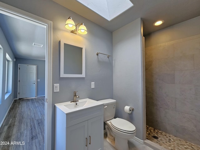 full bathroom with a skylight, visible vents, toilet, vanity, and tiled shower