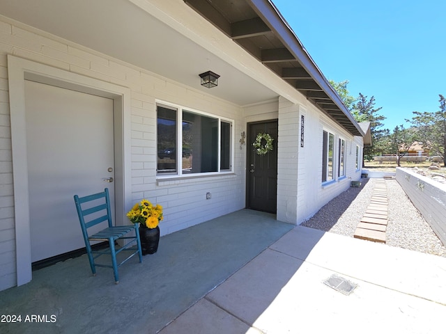 view of exterior entry featuring a patio and brick siding