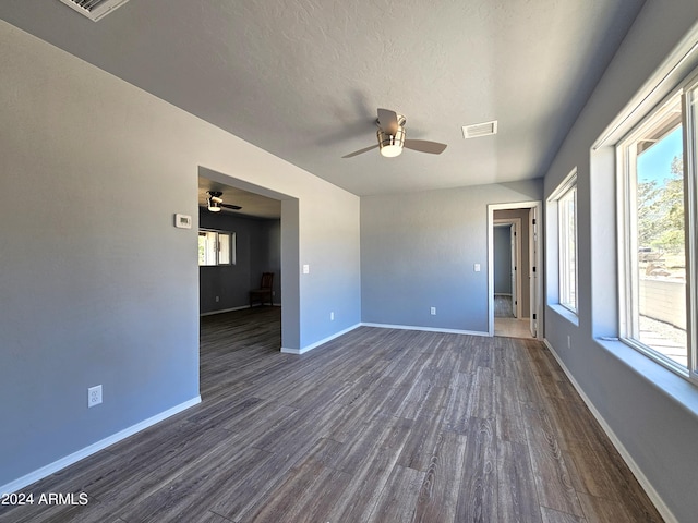 unfurnished room with dark wood-style floors, a textured ceiling, visible vents, and baseboards