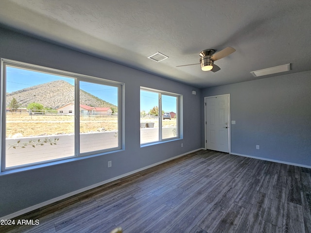 spare room with visible vents, dark wood-type flooring, a ceiling fan, a textured ceiling, and baseboards