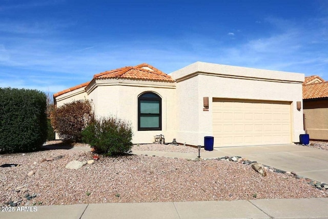 view of front of property featuring a tiled roof, concrete driveway, an attached garage, and stucco siding