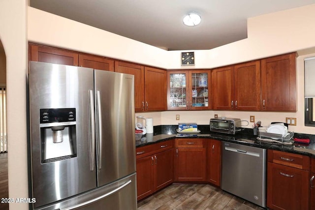 kitchen featuring a toaster, stainless steel appliances, brown cabinetry, glass insert cabinets, and dark wood-type flooring