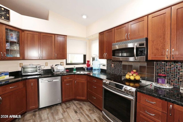 kitchen with lofted ceiling, a toaster, stainless steel appliances, a sink, and decorative backsplash