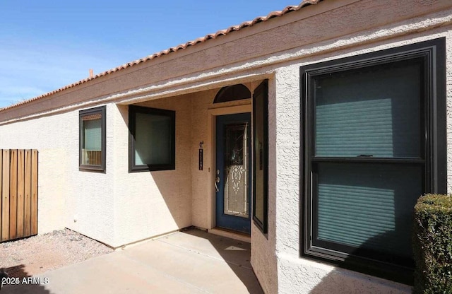 entrance to property with a tiled roof and stucco siding