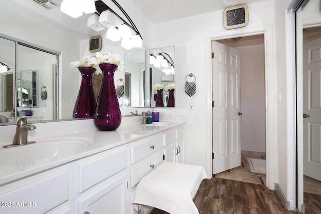 full bath featuring double vanity, visible vents, a sink, and wood finished floors