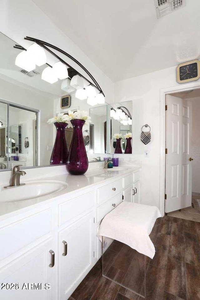 bathroom with double vanity, visible vents, a sink, and wood finished floors