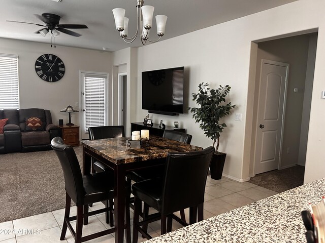 dining space with ceiling fan with notable chandelier and light carpet