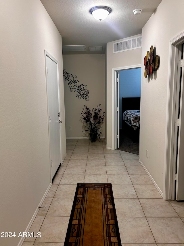 corridor with a textured ceiling and light tile patterned floors