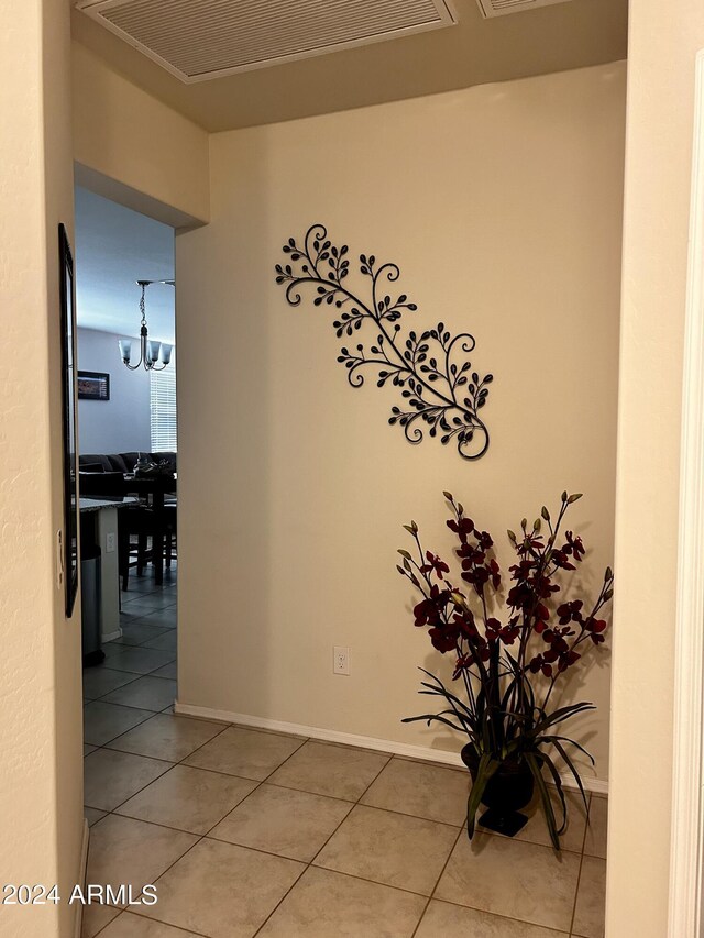 hallway featuring a notable chandelier and tile patterned flooring