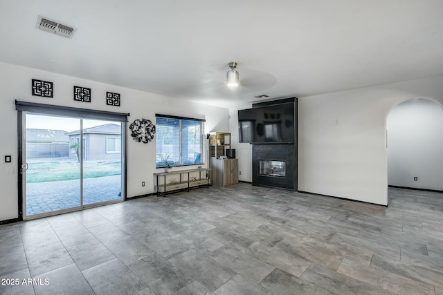 unfurnished living room with visible vents, arched walkways, baseboards, and a fireplace