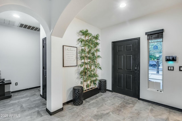 foyer entrance featuring arched walkways, baseboards, visible vents, and recessed lighting