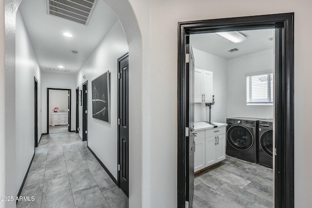 hall featuring separate washer and dryer, arched walkways, visible vents, and marble finish floor