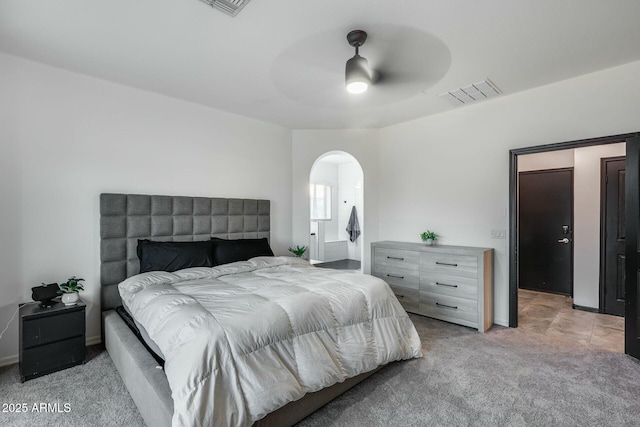 carpeted bedroom featuring visible vents, arched walkways, and ceiling fan