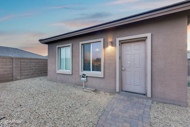 property entrance with fence and stucco siding