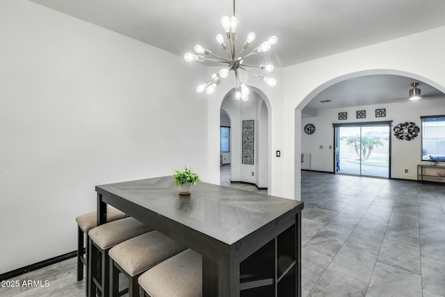 dining space with arched walkways and a chandelier