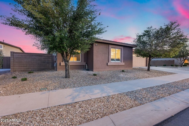 view of front of house with an attached garage, fence, and stucco siding