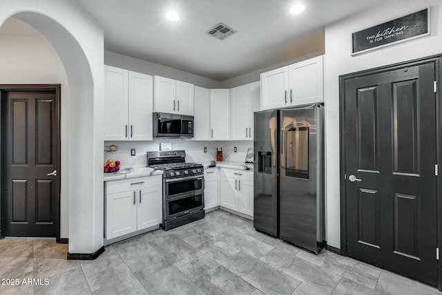 kitchen featuring visible vents, appliances with stainless steel finishes, arched walkways, light countertops, and white cabinetry