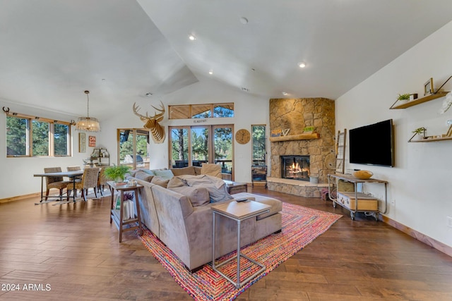 living room with dark hardwood / wood-style floors, a stone fireplace, and high vaulted ceiling