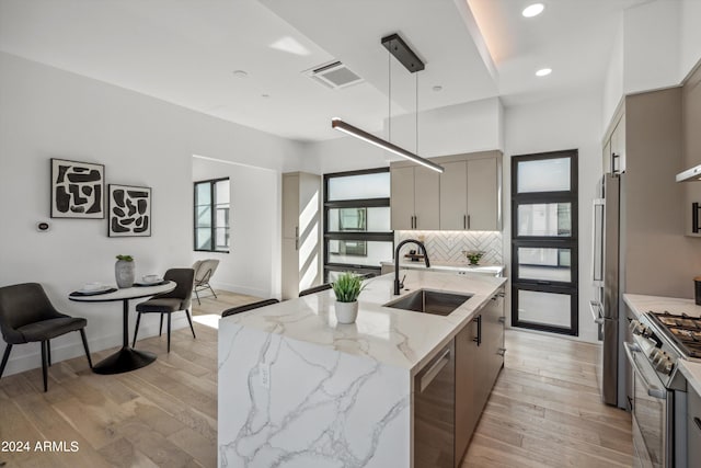 kitchen with gray cabinetry, sink, high end appliances, and light hardwood / wood-style flooring