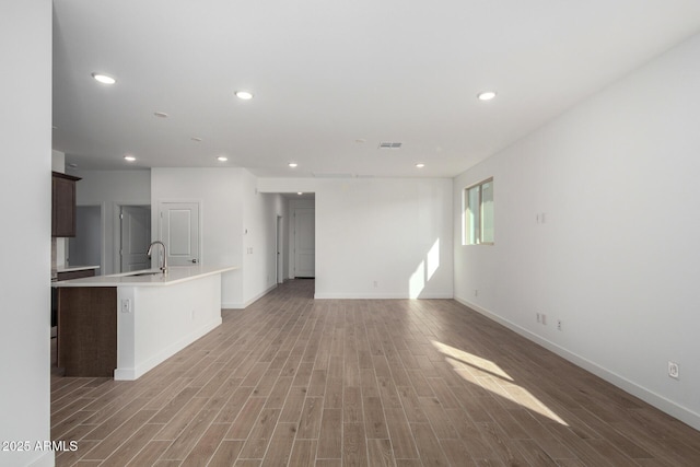 unfurnished living room featuring sink and hardwood / wood-style floors