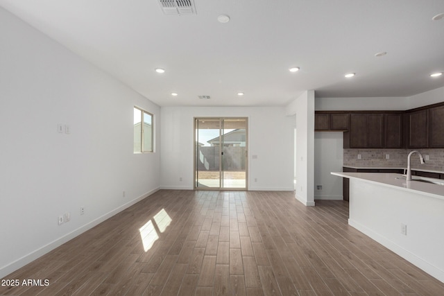 kitchen featuring dark brown cabinetry, sink, hardwood / wood-style floors, and backsplash