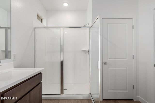 bathroom with walk in shower, vanity, and wood-type flooring