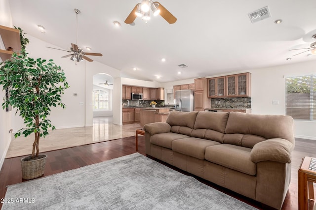 living room featuring ceiling fan, vaulted ceiling, and wood-type flooring