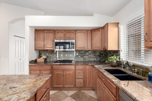 kitchen featuring stainless steel appliances, light stone countertops, sink, and decorative backsplash