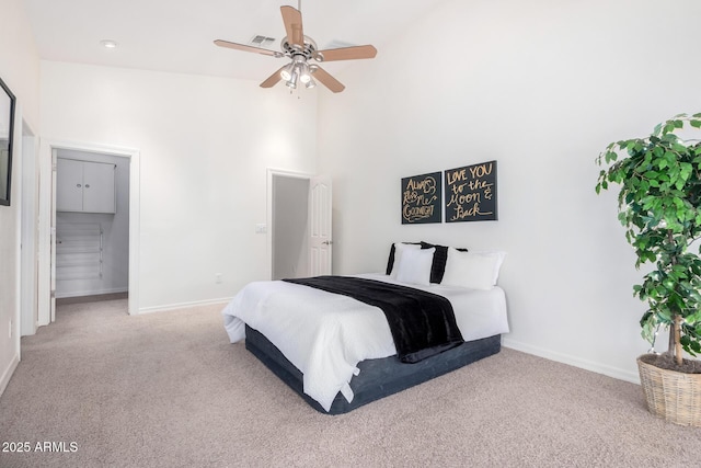 carpeted bedroom with ceiling fan and a high ceiling