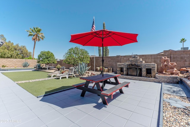 view of patio with an outdoor stone fireplace and a fenced backyard