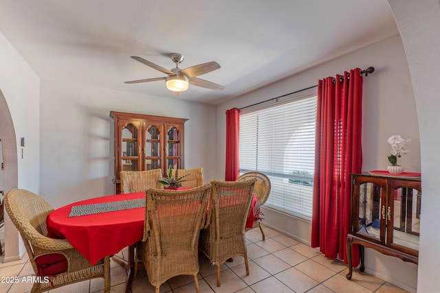 dining space with ceiling fan, light tile patterned flooring, and arched walkways
