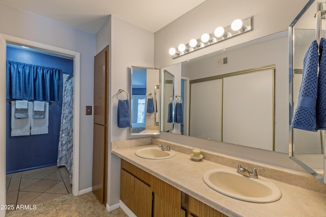 bathroom featuring double vanity, tile patterned floors, and baseboards