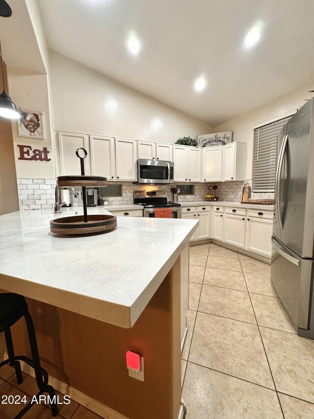 kitchen featuring stainless steel appliances, light countertops, white cabinets, vaulted ceiling, and a peninsula