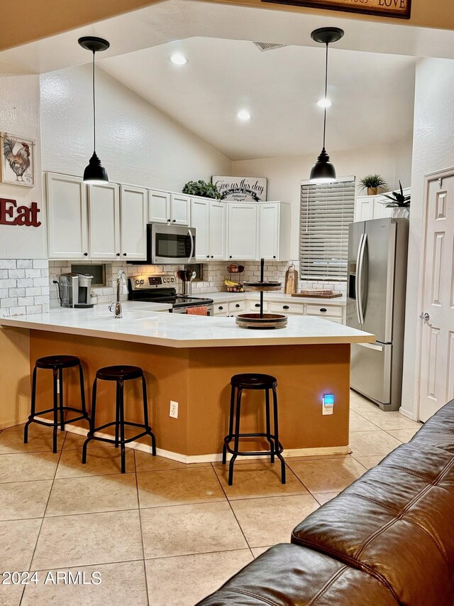 kitchen featuring appliances with stainless steel finishes, white cabinets, a sink, and a peninsula