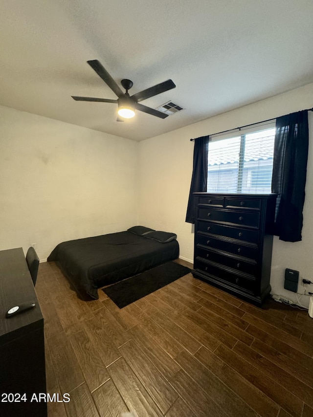 bedroom featuring ceiling fan, wood finished floors, visible vents, and baseboards