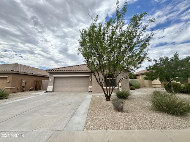 view of front of house with a garage, concrete driveway, a tiled roof, and stucco siding